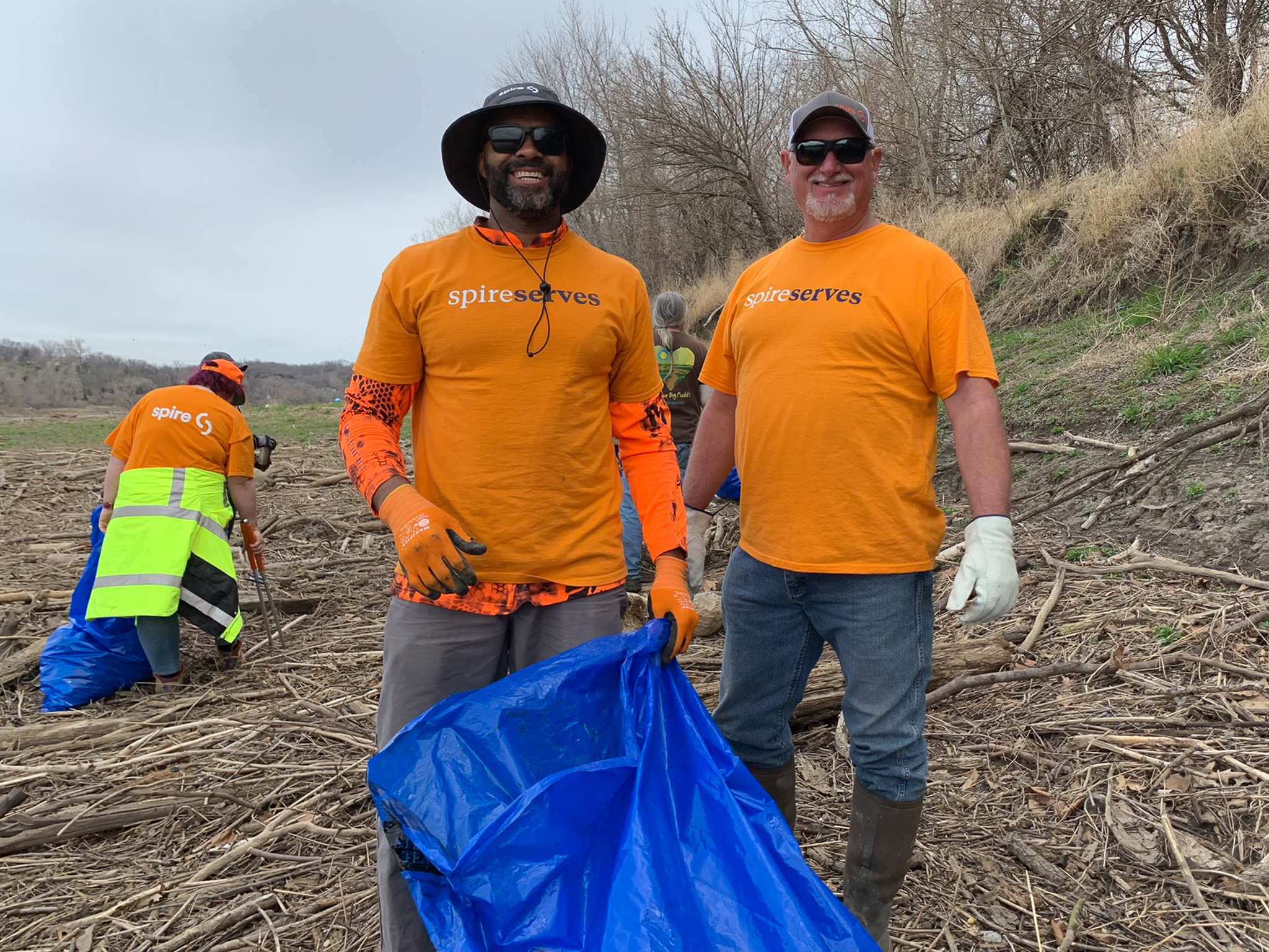 two men holding trash bag cleaning up