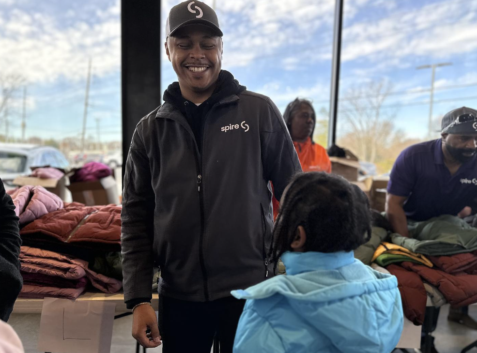 Image of Spire employee smiling at child receiving a coat at the coat drive