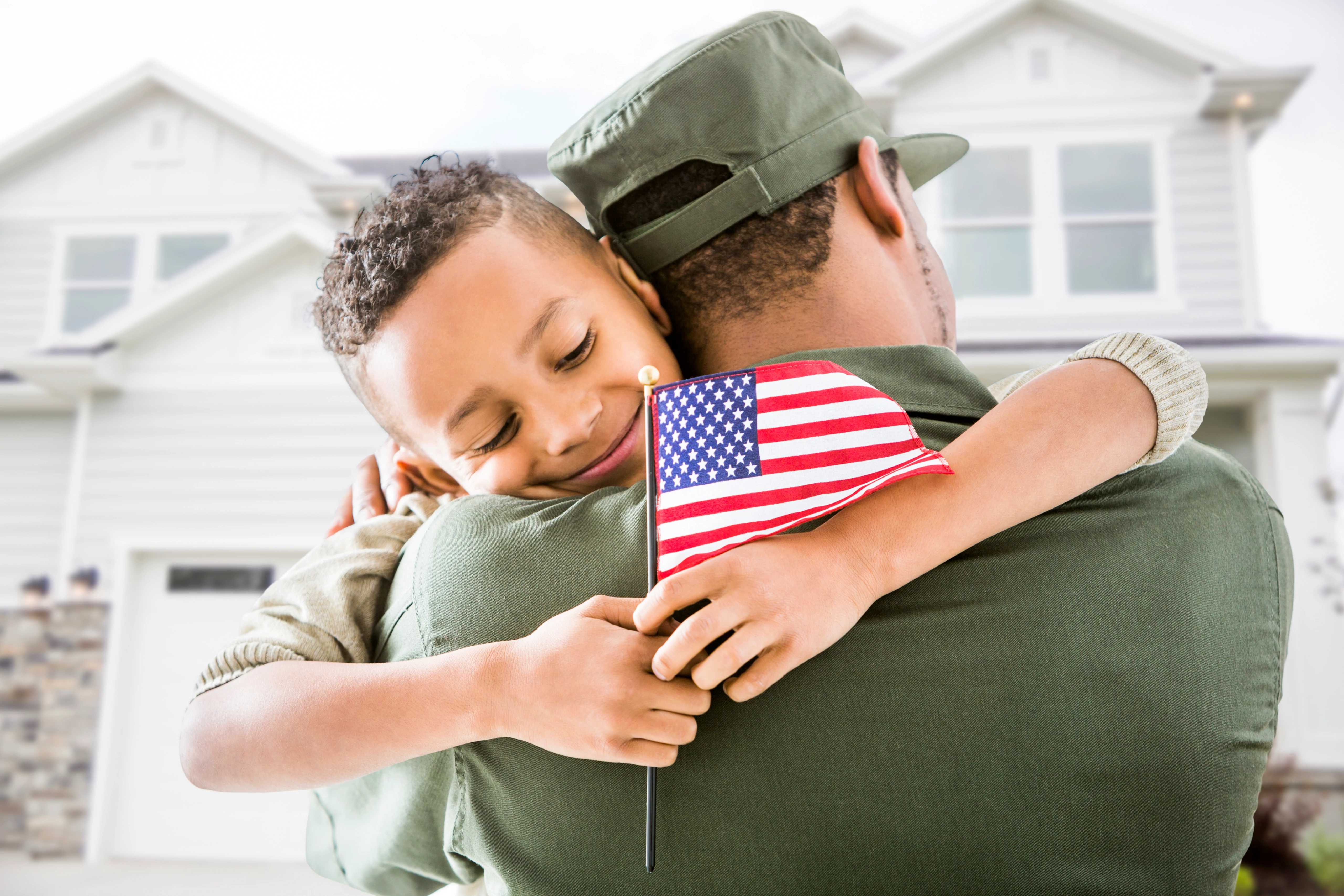Image of father hugging his son while holding an American flag