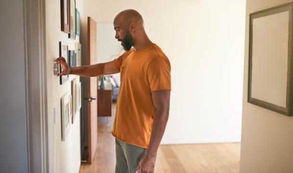 Image of homeowner adjusting programmable thermostat