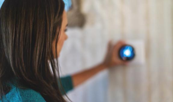 Image of woman adjusting a smart thermostat to an energy-efficient temperature