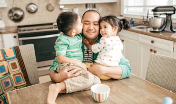 Image of family hugging in kitchen
