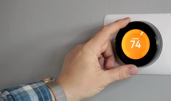 Image of hand adjusting smart thermostat