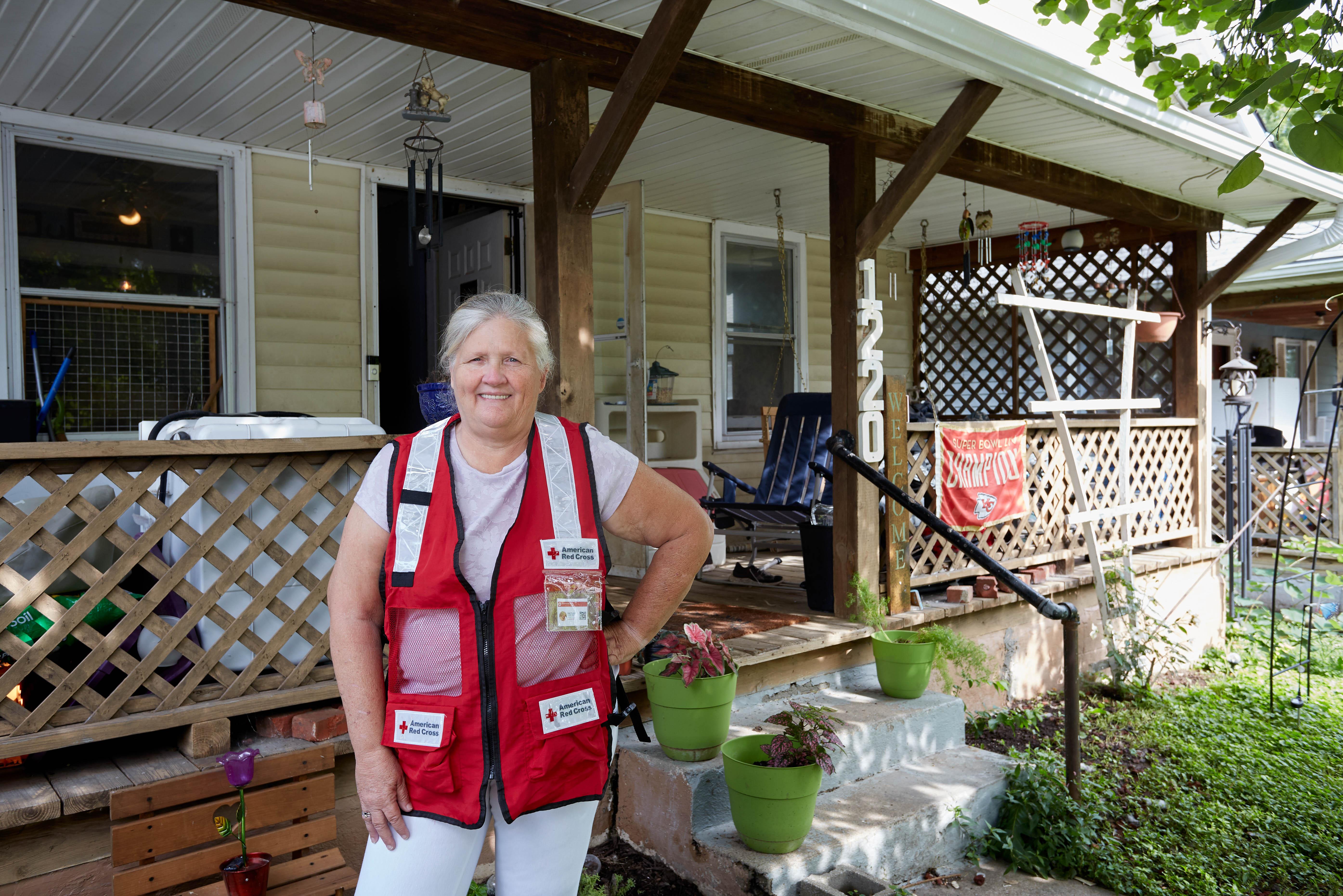 Image of: Red Cross volunteer standing in front of her home