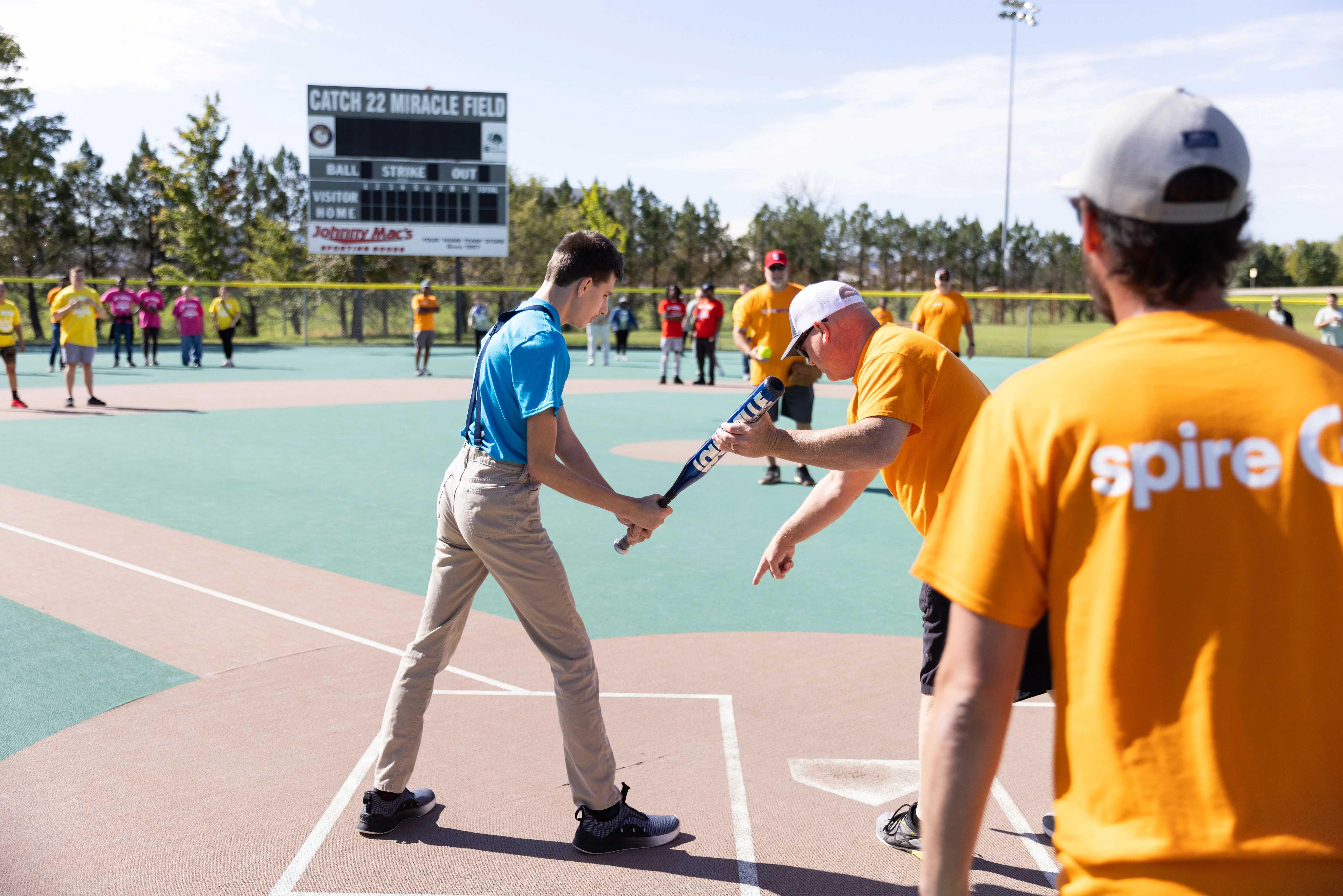 Spire volunteers helping person with baseball bat 