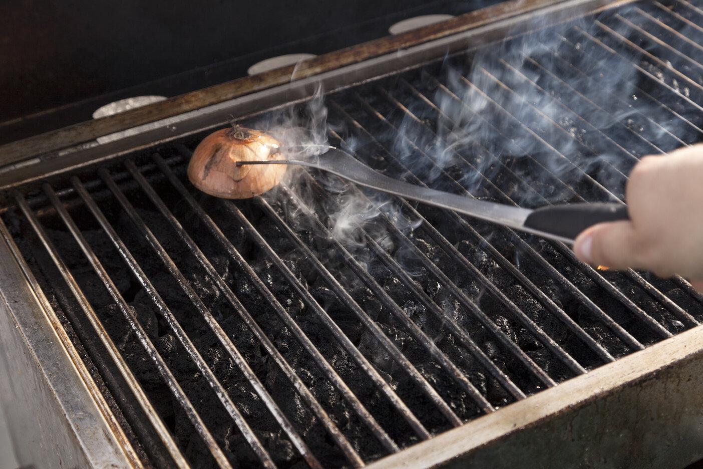 Image of person cleaning a grill with an onion