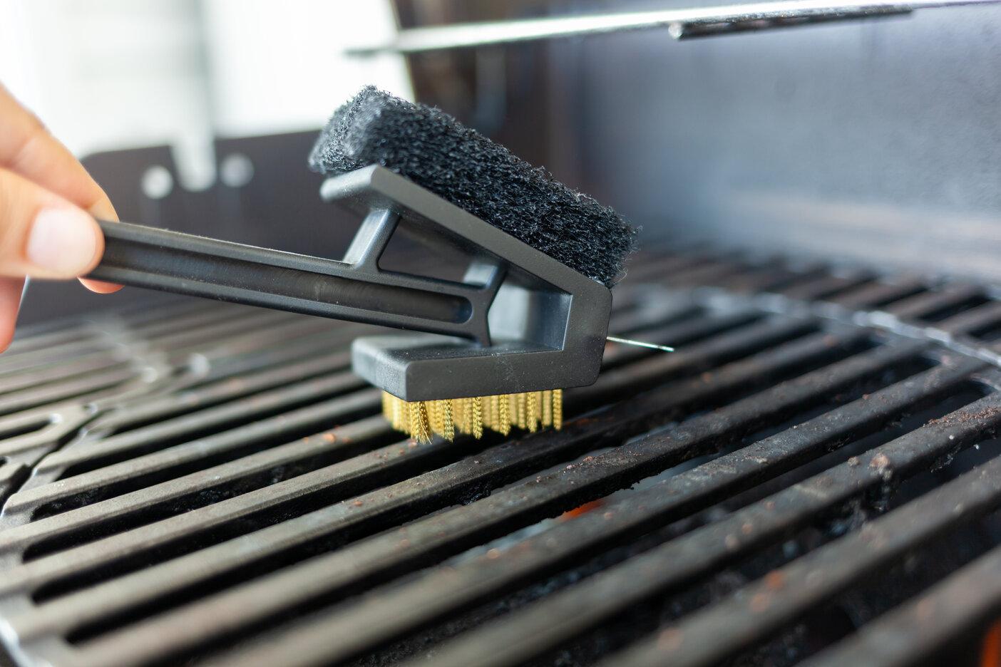 Image of person cleaning their grill with a non-metal brush