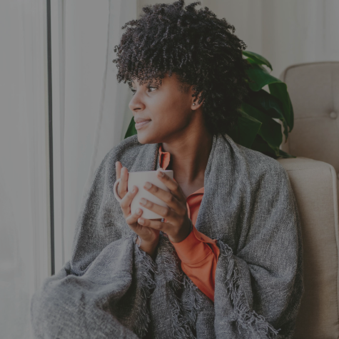 Image of woman snuggling by her window holding a coffee cup
